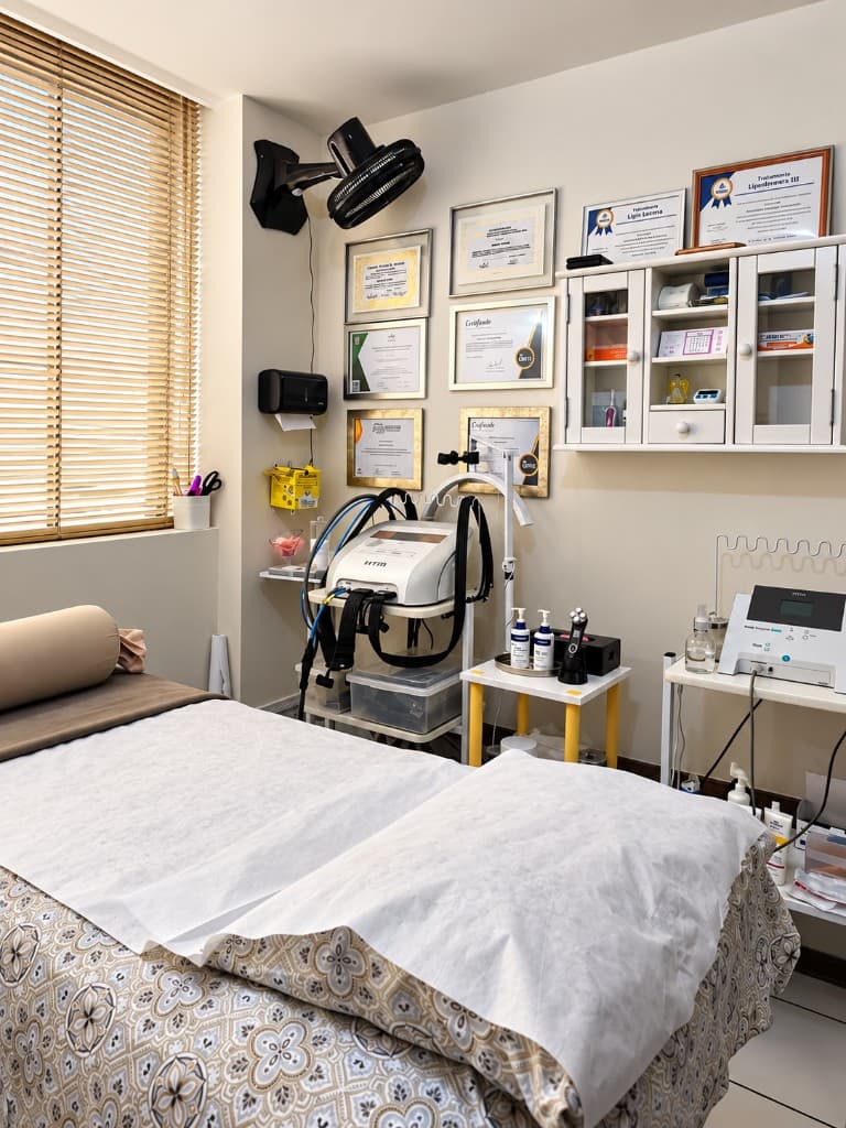Sala de atendimento com maca e equipamentos de fisioterapia dermatofuncional
